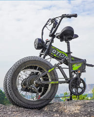 Black - OTIDA R7 MAX Dual Motor Electric Bike with green accents on a rocky surface with a cityscape in the background