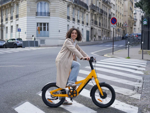 Woman riding a yellow Heybike EC Compact City Electric bicycle on a city street