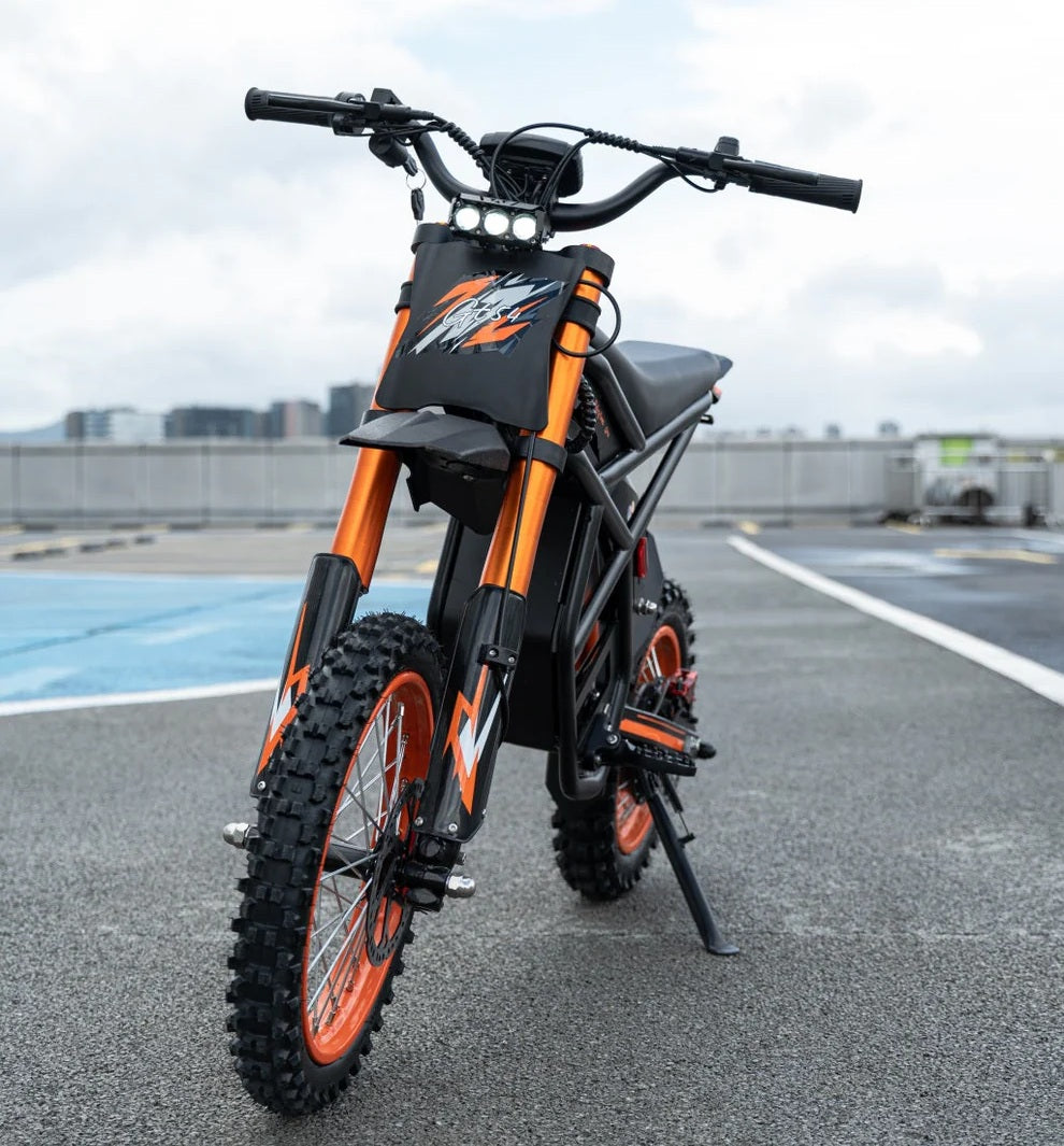 Riding Times GT54 Electric Bike in black and orange on a road with a cityscape in the background
