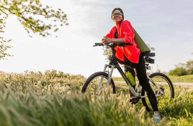 Electric bike side view outdoors with woman smiling in grassy field