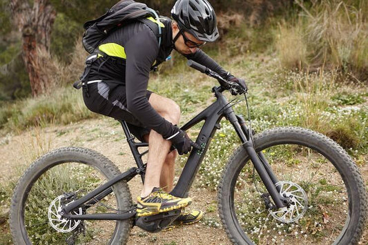 electric mountain bike in matte black with large tires side view on off-road trail