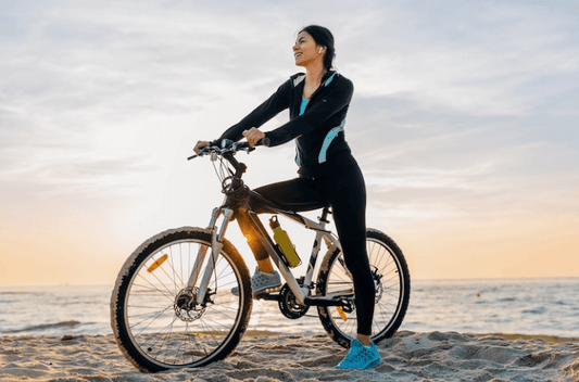 Woman riding a fat tire electric bike on the beach at sunset, side view